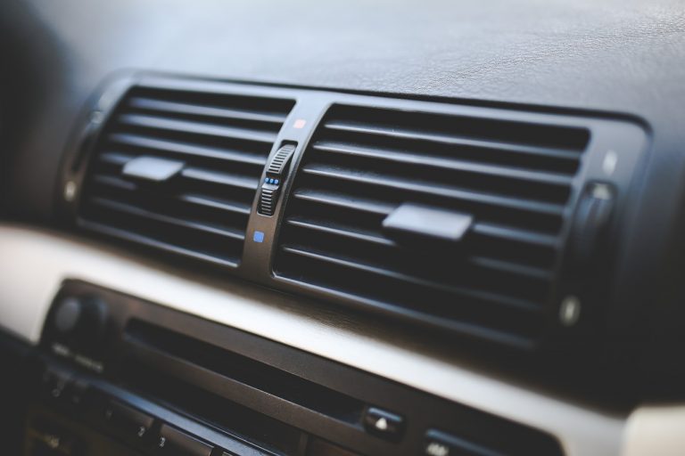 A close up of a black car dashboard and air con system