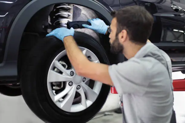worker inspecting a shock absorber on a car.